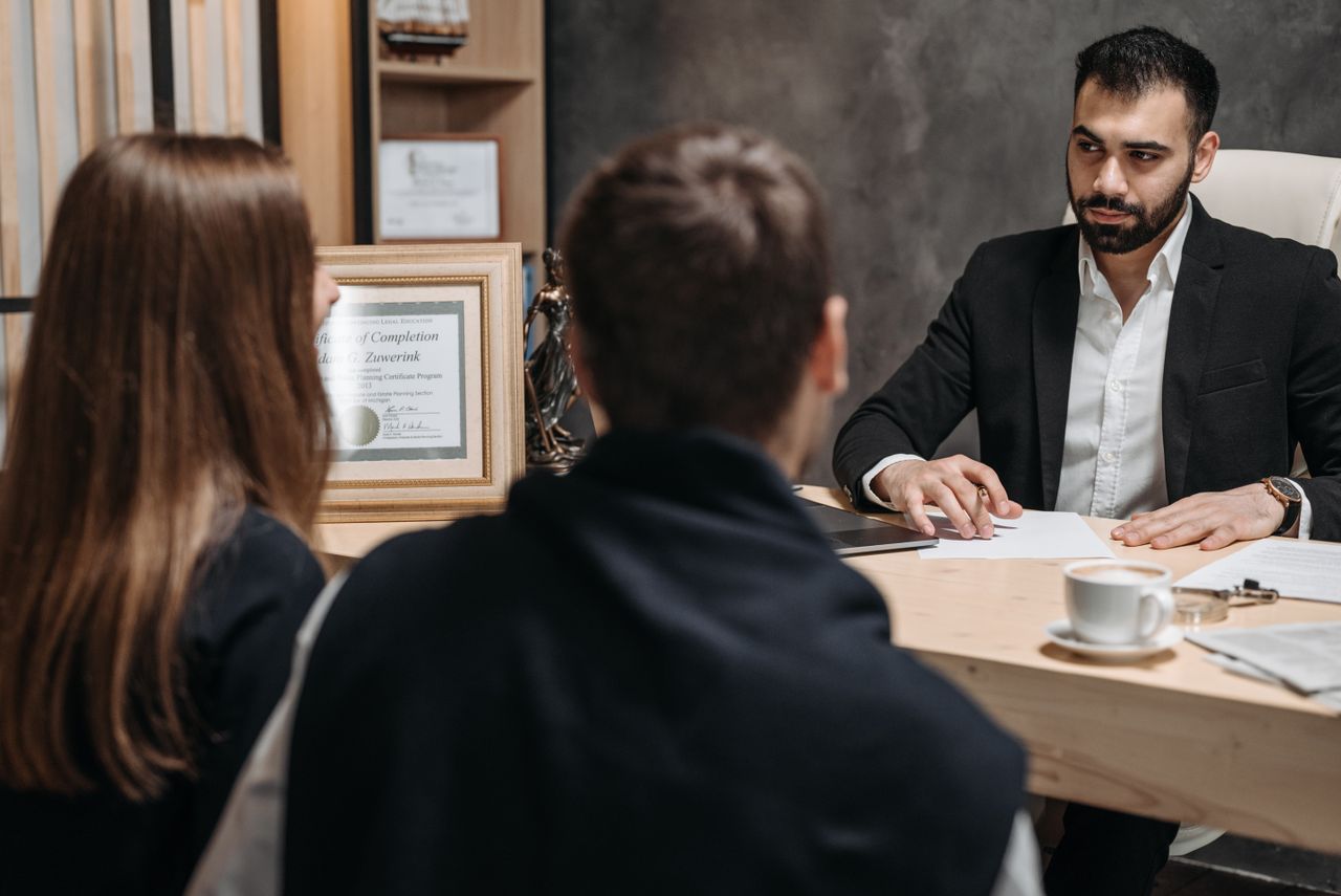 home-hero-bg A lawyer in an elegant office meeting with clients, discussing documents.
