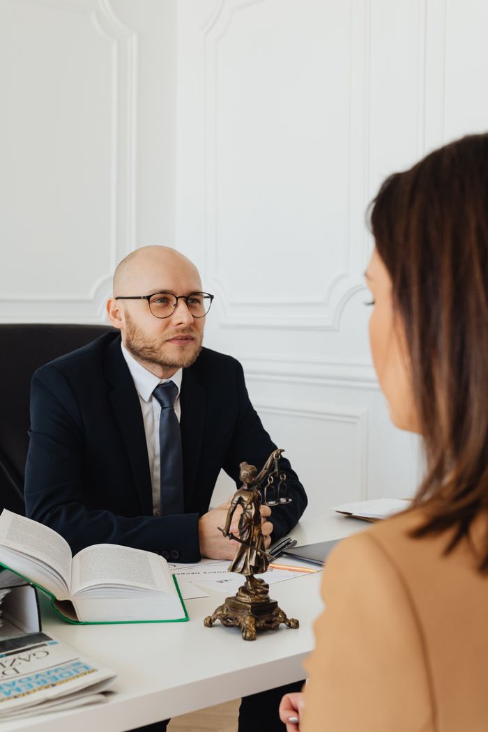 home-services-01 A lawyer consulting with a client in a modern office featuring Lady Justice.